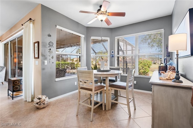 dining space featuring a ceiling fan, a wealth of natural light, baseboards, and light tile patterned floors