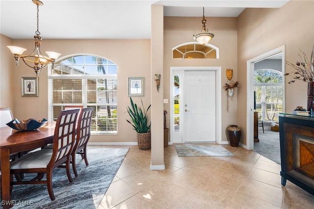 entrance foyer featuring light tile patterned floors, baseboards, a wealth of natural light, and an inviting chandelier