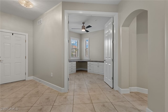 foyer entrance with ceiling fan, light tile patterned floors, and built in desk