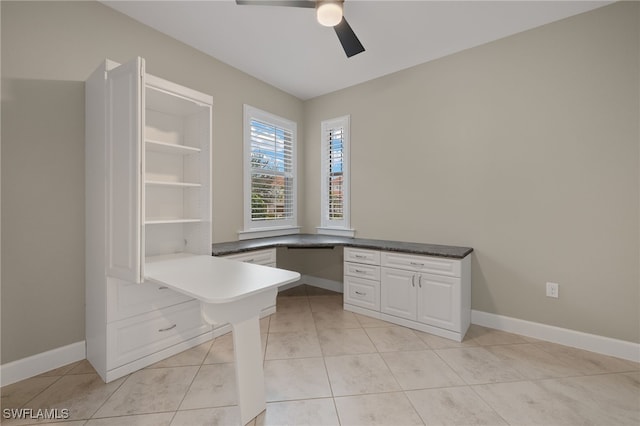 unfurnished office featuring ceiling fan, built in desk, and light tile patterned flooring