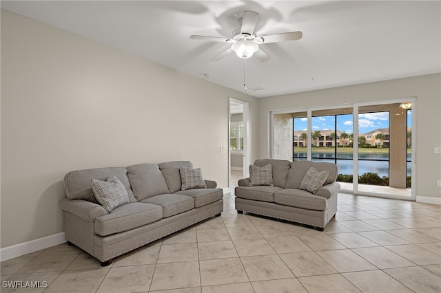 tiled living room featuring ceiling fan and a water view