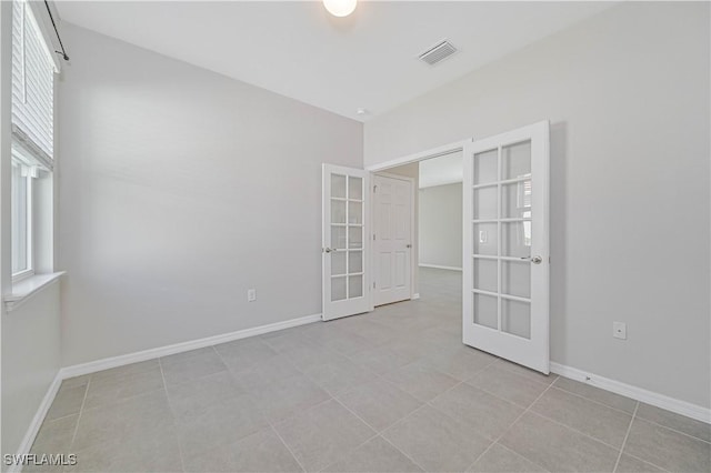 tiled spare room featuring french doors and plenty of natural light