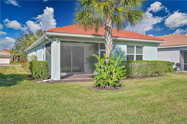 15133 Ligustrum Ln, Alva, FL 33920 - back of property with a tiled roof, a lawn, stucco siding, and a sunroom