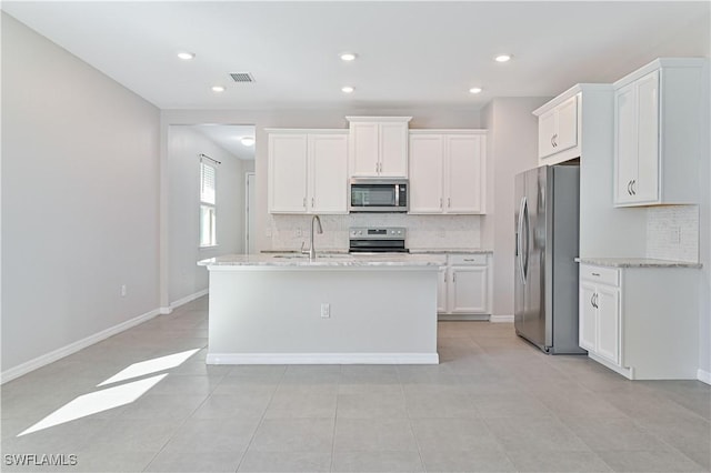 15133 Ligustrum Ln, Alva, FL 33920 - kitchen with appliances with stainless steel finishes, backsplash, white cabinets, a sink, and a center island with sink