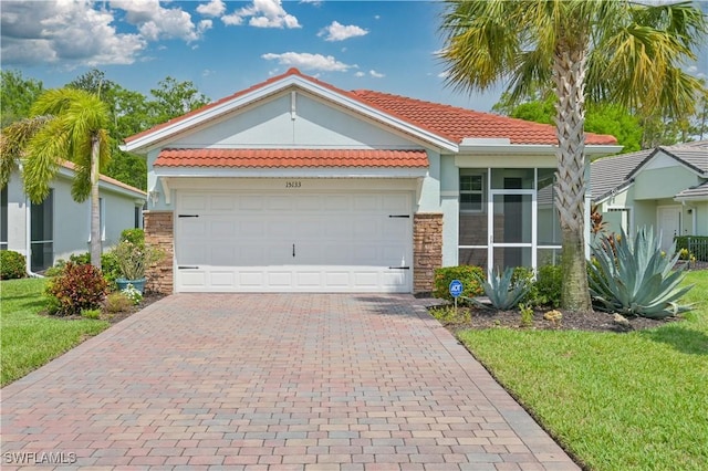 15133 Ligustrum Ln, Alva, FL 33920 - view of front of property with a tiled roof, decorative driveway, stucco siding, a front lawn, and stone siding