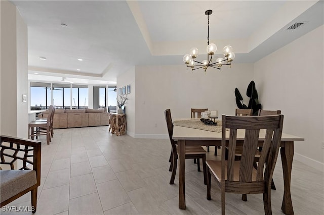 dining space with an inviting chandelier and a tray ceiling