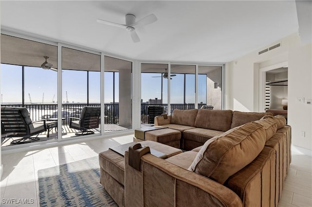 living room featuring ceiling fan, light tile patterned floors, and expansive windows