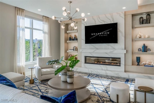 living room featuring a notable chandelier, a high end fireplace, and built in shelves