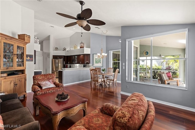 living room with ceiling fan with notable chandelier, lofted ceiling, and dark wood-type flooring