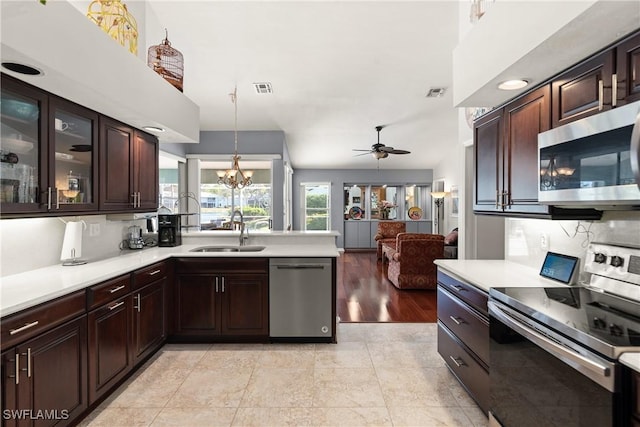 kitchen with sink, ceiling fan with notable chandelier, dark brown cabinetry, pendant lighting, and appliances with stainless steel finishes