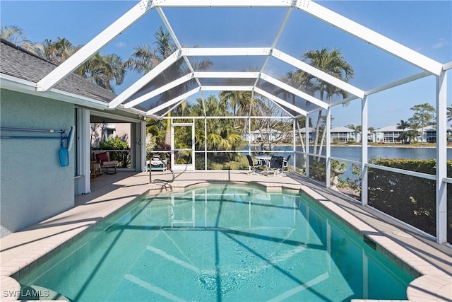 view of pool with a water view, glass enclosure, and a patio area