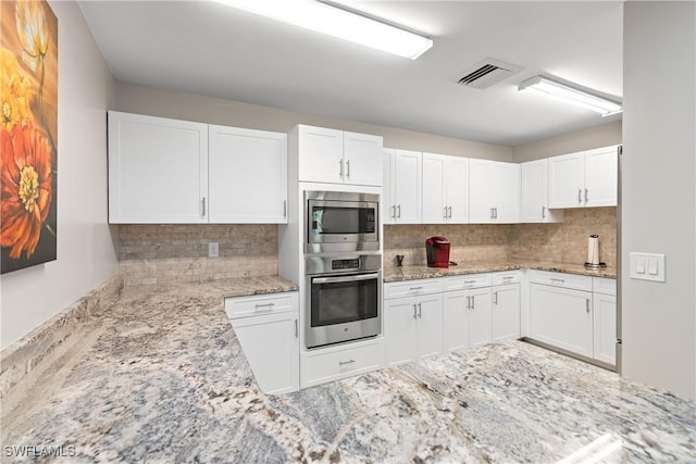 kitchen with stainless steel appliances, white cabinetry, light stone counters, and tasteful backsplash