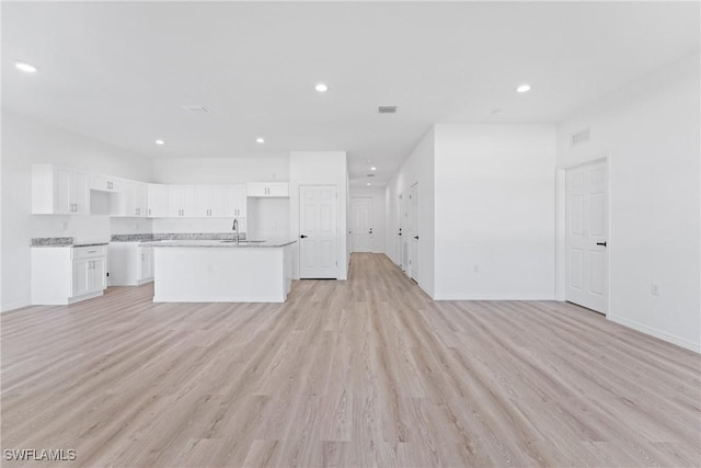 unfurnished living room featuring light wood-type flooring and sink