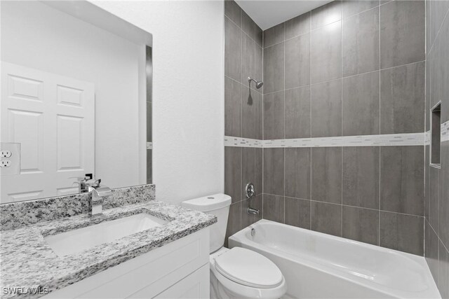 full bathroom with vanity, tiled shower / bath combo, and toilet