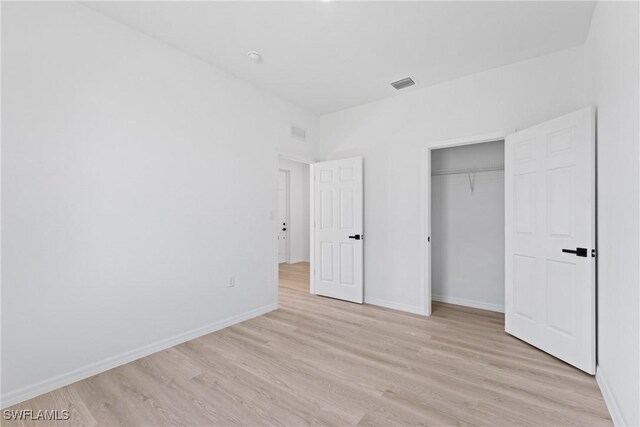 unfurnished bedroom with light hardwood / wood-style floors and a closet