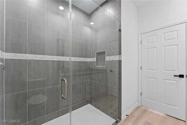 bathroom featuring a shower with shower door and hardwood / wood-style flooring