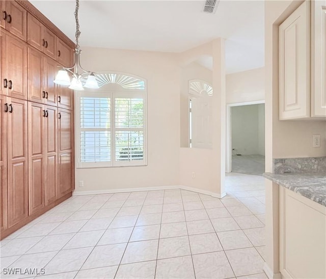 unfurnished dining area with light tile patterned floors and a notable chandelier