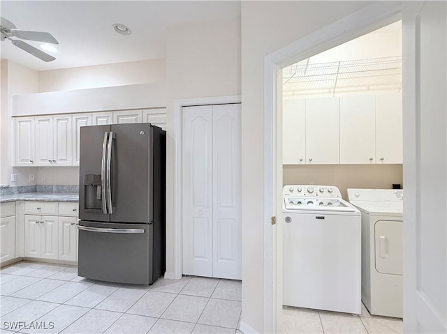 interior space featuring washing machine and clothes dryer, ceiling fan, light tile patterned floors, and cabinets