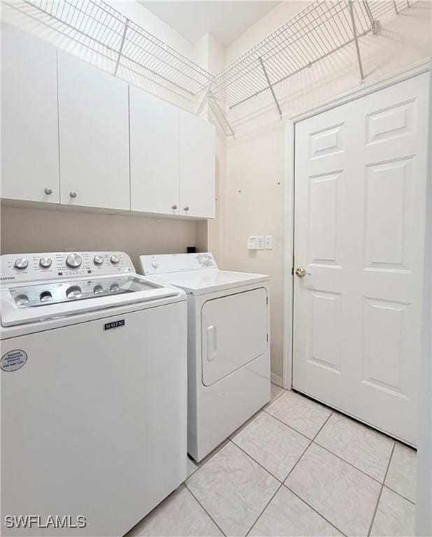 laundry room with washing machine and clothes dryer, light tile patterned flooring, and cabinets