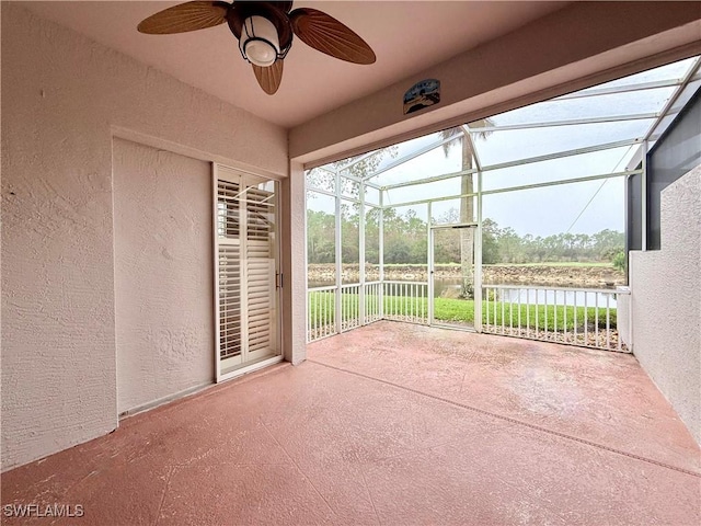 unfurnished sunroom with ceiling fan and a water view