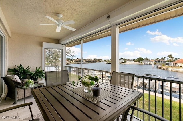 sunroom with ceiling fan and a water view