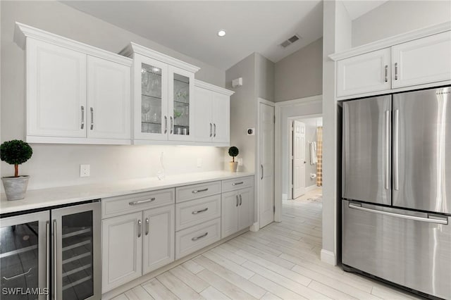 kitchen featuring wine cooler, stainless steel fridge, white cabinetry, and light hardwood / wood-style flooring