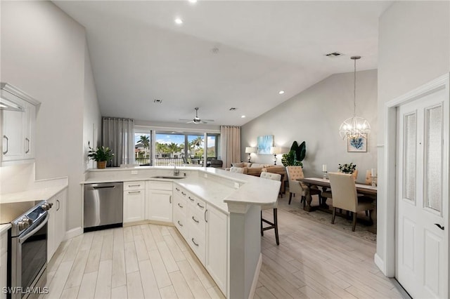 kitchen with ceiling fan with notable chandelier, white cabinets, appliances with stainless steel finishes, decorative light fixtures, and kitchen peninsula