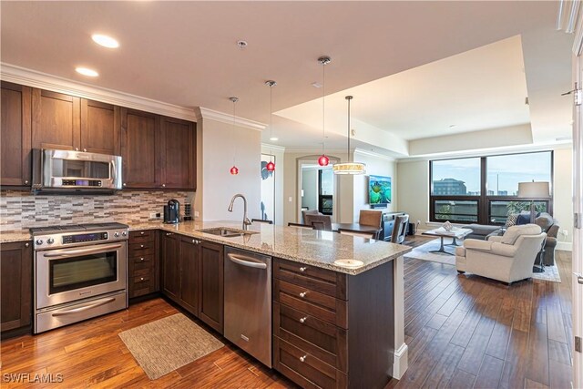 kitchen featuring stainless steel appliances, a sink, a peninsula, dark wood-style flooring, and decorative backsplash