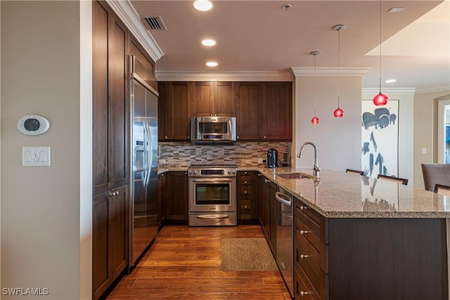 kitchen with stainless steel appliances, backsplash, ornamental molding, a sink, and a peninsula