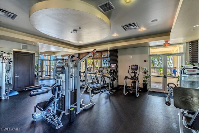 exercise room with a tray ceiling, french doors, and visible vents