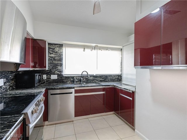 kitchen with sink, stainless steel appliances, backsplash, dark stone counters, and light tile patterned floors