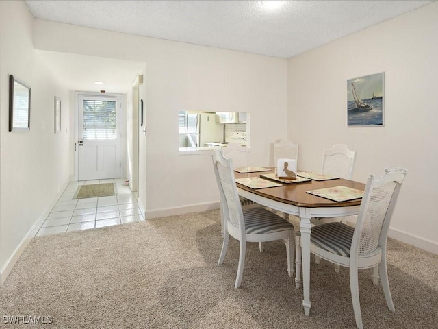 dining area with light carpet and a textured ceiling