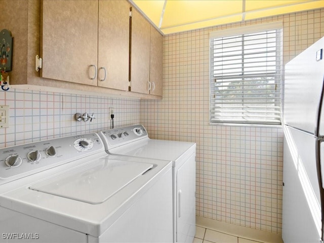 clothes washing area featuring tile patterned floors, washer and dryer, plenty of natural light, and cabinets