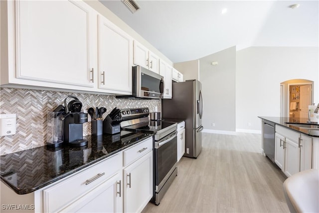 kitchen featuring appliances with stainless steel finishes, tasteful backsplash, sink, dark stone countertops, and white cabinets