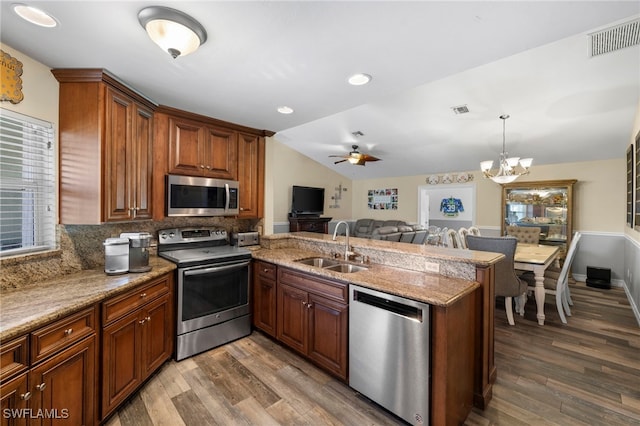 kitchen with ceiling fan with notable chandelier, sink, kitchen peninsula, and stainless steel appliances