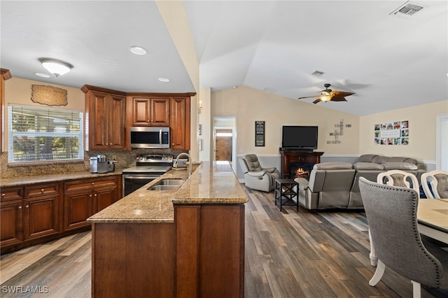 kitchen featuring appliances with stainless steel finishes, dark wood-type flooring, sink, backsplash, and vaulted ceiling