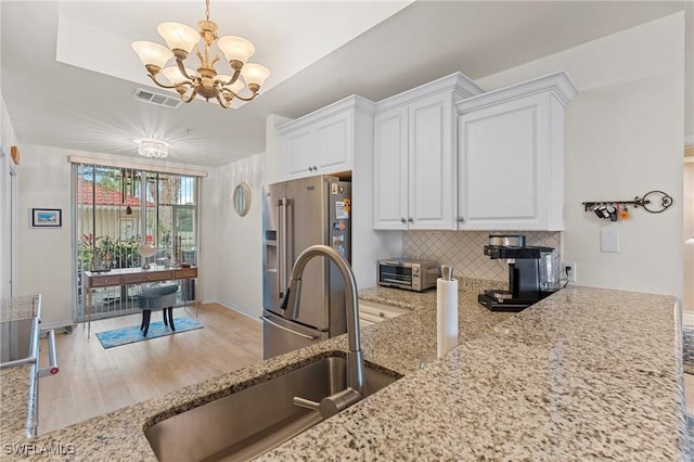 kitchen featuring sink, an inviting chandelier, high end refrigerator, pendant lighting, and white cabinets