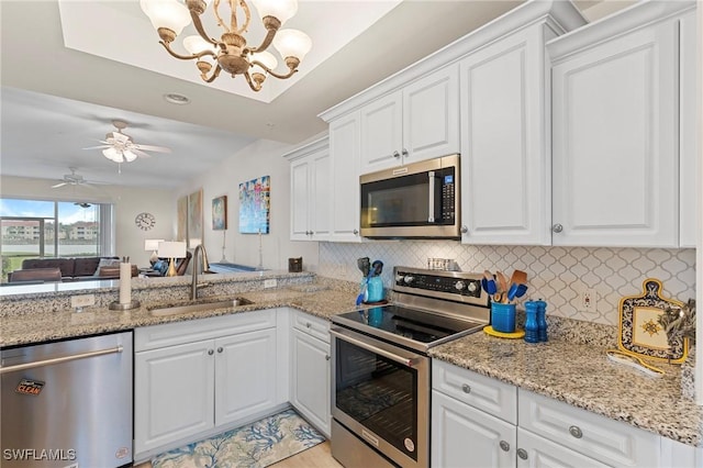 kitchen with sink, ceiling fan with notable chandelier, stainless steel appliances, and white cabinets