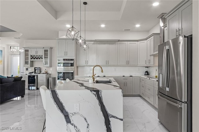 kitchen featuring sink, beverage cooler, pendant lighting, gray cabinets, and appliances with stainless steel finishes