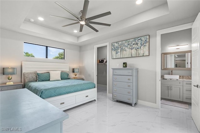 bedroom with a raised ceiling, sink, ceiling fan, a spacious closet, and connected bathroom