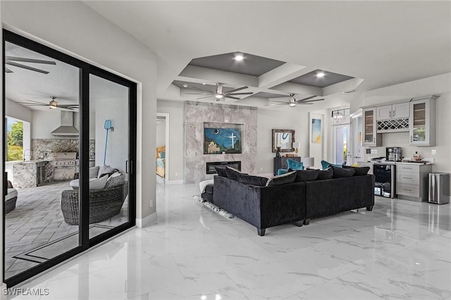 living room with coffered ceiling, beam ceiling, a premium fireplace, wine cooler, and bar