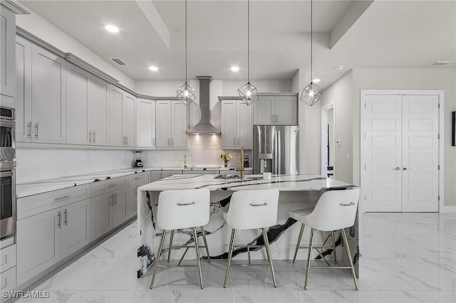 kitchen featuring pendant lighting, a breakfast bar, wall chimney range hood, a large island, and stainless steel appliances