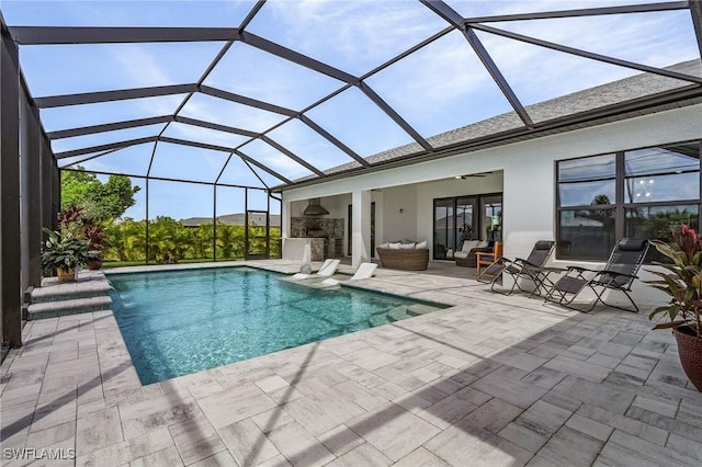 view of pool with pool water feature, an outdoor living space, ceiling fan, glass enclosure, and a patio area