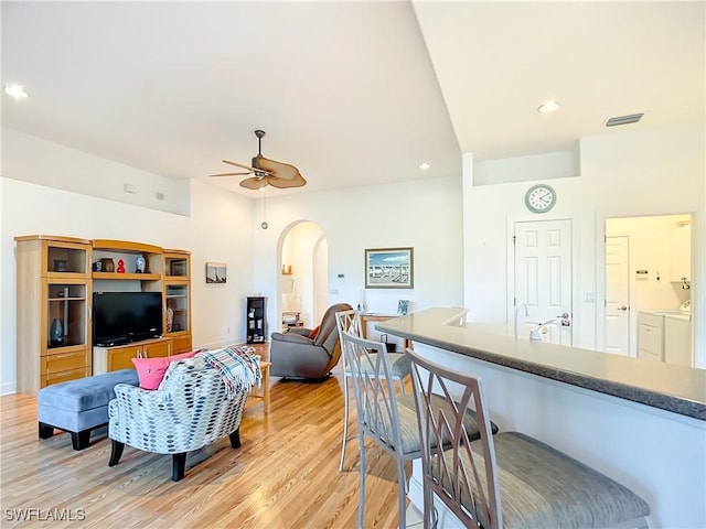 living room with light hardwood / wood-style floors, washer and dryer, and ceiling fan