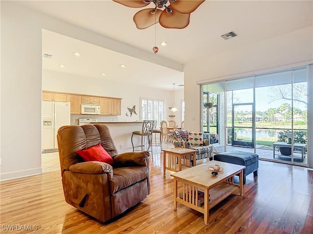 living room featuring ceiling fan, a healthy amount of sunlight, and light hardwood / wood-style flooring