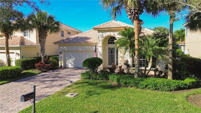 mediterranean / spanish home featuring a garage and a front yard