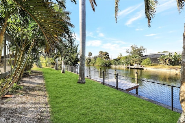 view of dock with a lawn and a water view