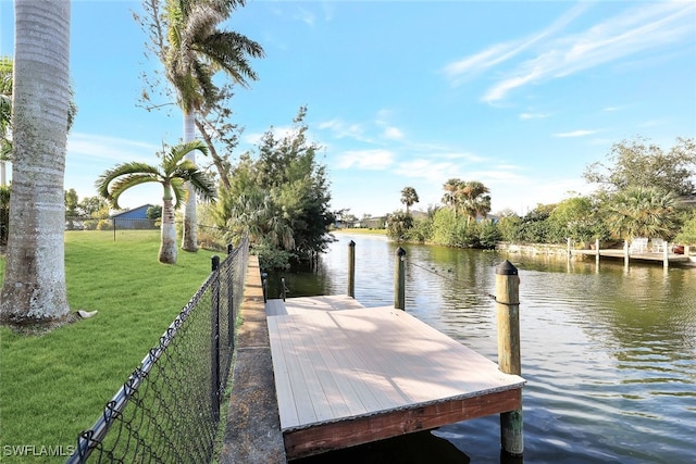 view of dock with a yard and a water view