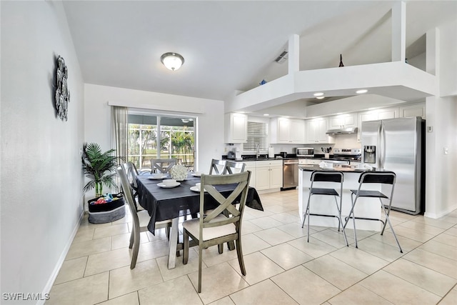 tiled dining area featuring sink and high vaulted ceiling