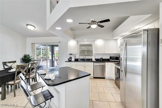 kitchen featuring white cabinetry, sink, ceiling fan, a tray ceiling, and appliances with stainless steel finishes